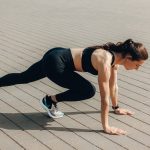 Woman in black sportswear doing an outdoor workout on a sunny day.