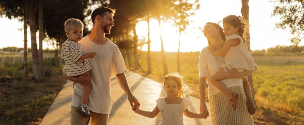 A joyful family walking together on a sunlit path during sunset, enjoying an outdoor stroll.