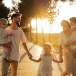 A joyful family walking together on a sunlit path during sunset, enjoying an outdoor stroll.