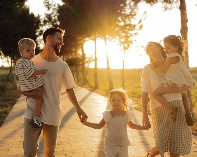 A joyful family walking together on a sunlit path during sunset, enjoying an outdoor stroll.